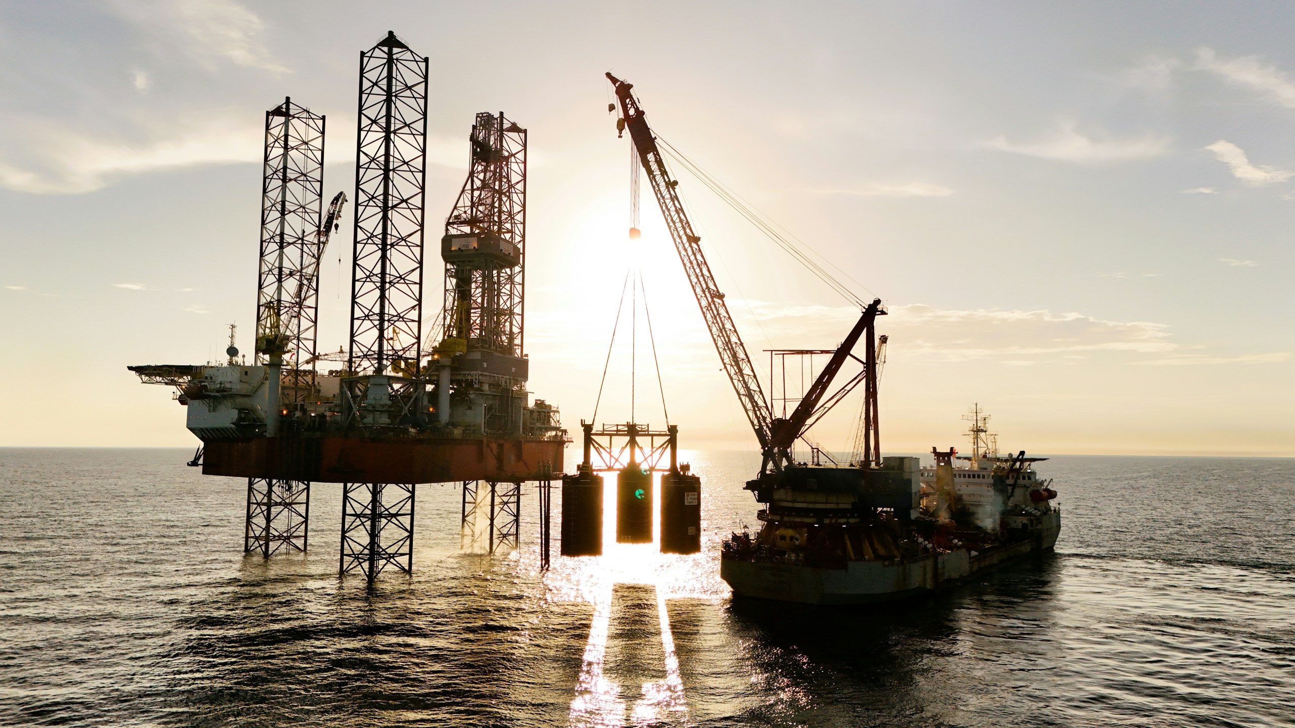 Offshore drilling rig being serviced by a supply vessel at sea